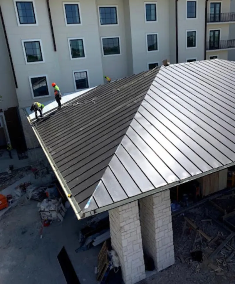 Crew installing standing seam metal roof panels on a commercial project in Krum